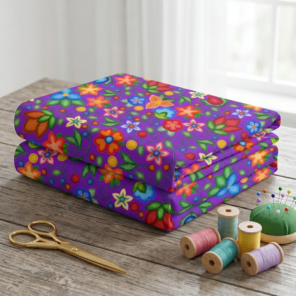 Morning Harmony Purple cotton poplin fabric folded in a stack on a wooden table with scissors and spools of thread